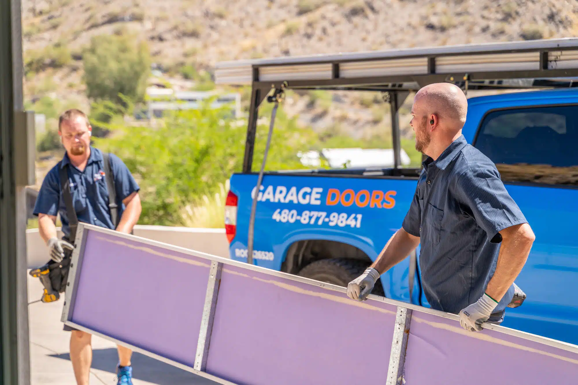 Two Blue Fox technicians moving a garage door panel